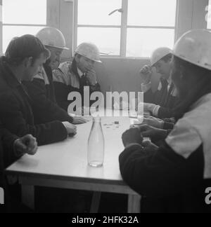 Aeroporto di Heathrow, BEA Servicing Hangar, Heathrow, Hillingdon, Londra, 07/04/1970. Operai di Laing che giocano un gioco di carte ad un tavolo nella mensa del sito durante la costruzione del velivolo BEA che serve l'hangar all'aeroporto di Heathrow. Nell'ottobre 1969 Laing ha annunciato che la sua filiale di Ingegneria industriale aveva ricevuto un contratto per la costruzione di un hangar di servizio per la British European Airways all'aeroporto di Heathrow. È stato il secondo contratto principale della società&#x2019 a Heathrow, in seguito al completamento del terminal merci BEA e BOAC. Foto Stock