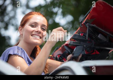 sciatore femmina che fissa gli sci ai binari del tetto dell'auto Foto Stock