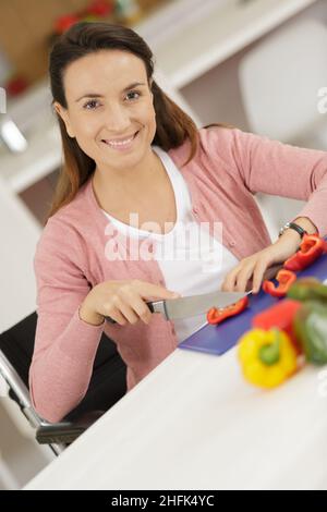 donna felice che taglia le verdure in cucina Foto Stock