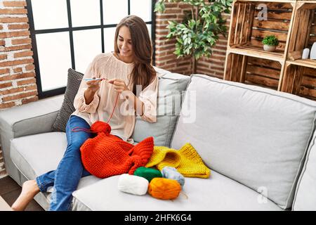 Giovane ispanica sorridente fidata tessendo in finisce a casa Foto Stock