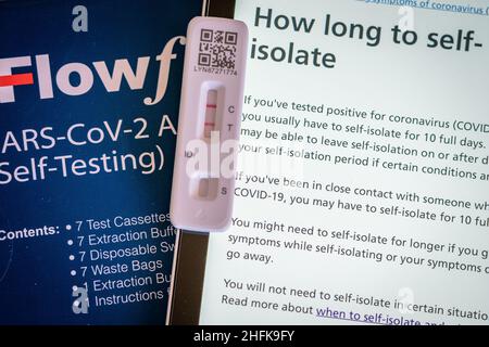 Una cassetta per test a flusso laterale positiva posta accanto ai consigli del sito web NHS, a Londra. L'Agenzia per la sicurezza sanitaria del Regno Unito ha detto che le persone in Inghilterra possono essere in grado di lasciare l'autoisolamento il giorno 6 del vostro periodo di autoisolamento se avete 2 test negativi il giorno 5 e 6. Data foto: Lunedì 17 gennaio 2022. Foto Stock