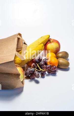 Shopping e consegna di cibo sano su sfondo bianco. Cibo vegetariano vegano sano in un sacchetto di carta. Mangiare sano contro il covid Foto Stock