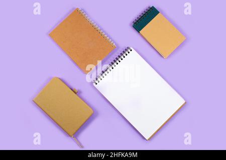 Tavolo da ufficio da diversi notebook e calendario su sfondo viola. Obiettivi e piani per il prossimo anno 2022. Vista dall'alto, disposizione piatta Foto Stock