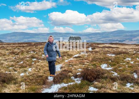 Un camminatore che cammina via dal cairn del Signore Arthur sulla collina del Signore Arthur nelle colline di Correen vicino ad Alford, Aberdeenshire, Scozia Foto Stock