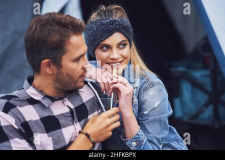 Giovane bella coppia divertirsi in campeggio condividere drink Foto Stock