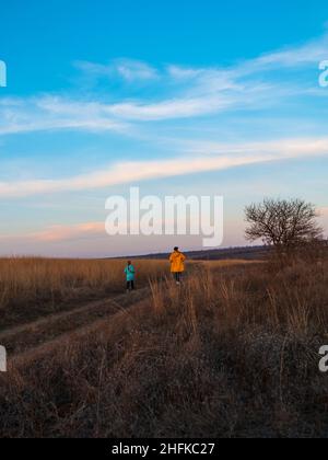 I viaggiatori padre figlia camminare insieme su collina godendo paesaggio panoramico blu nuvoloso tramonto cielo escursionistico percorso Foto Stock