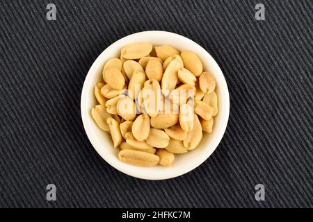 Vista dall'alto delle arachidi salate in ciotola su tessuto blu Foto Stock