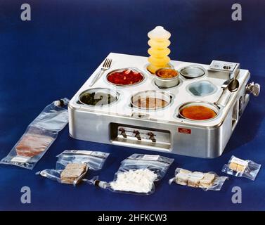 (1972) -- una vista ravvicinata di un vassoio per alimenti che dovrebbe essere utilizzato nel programma Skylab. Diverse confezioni di cibo spaziale si trovano accanto al vassoio. Il cibo nel vassoio è pronto per mangiare. Fuori vassoio, a partire dal basso a sinistra: Bevanda all'uva, arrosto in pentola di manzo, pollo e riso, sandwich di manzo e cubetti di biscotti allo zucchero. Nel vassoio, dal retro a sinistra: Bevanda all'arancia, fragole, asparagi, costolette di prima qualità, panino per la cena e budino di farfalle al centro. Foto Stock