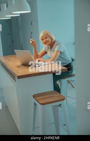 Sorridente donna anziana che usa un computer portatile a casa Foto Stock