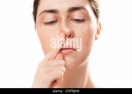 Chirurgia plastica del naso. Primo piano volto della giovane donna caucasica che tocca il suo naso storto isolato su sfondo bianco. Concetto di rinoplastica. Foto Stock