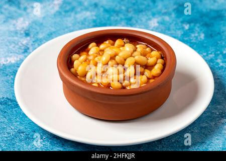 Stufato di fagiolo turco caldo su sfondo blu. Fagioli di Ispir cotti in una casseruola - Kuru Fasulye Foto Stock