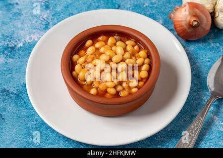 Stufato di fagiolo turco caldo su sfondo blu. Fagioli di Ispir cotti in una casseruola - Kuru Fasulye Foto Stock