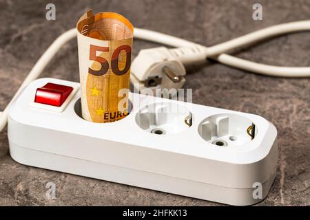 Banconota da 50 euro inserita in una presa di prolunga. Aumento dei costi dell'elettricità per gli utenti aziendali e i clienti residenziali. Aumento di electricit Foto Stock