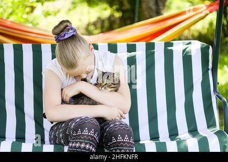 Gatto a righe seduto nelle mani di una ragazza adolescente Foto Stock