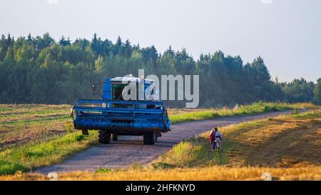 La mietitrebbiatrice ritorna dal lavoro sul campo in una serata libera. Luce solare e campi raccolti. Paesaggio rurale. Foto Stock