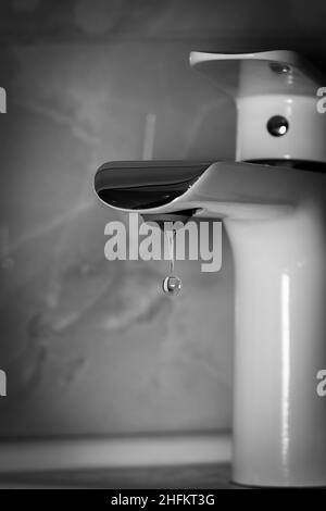 Goccia d'acqua limpida che cade dal rubinetto. Foto in bianco e nero a contrasto. Foto Stock