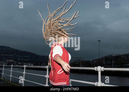 donna bionda con dreadlocks che si aggira i capelli Foto Stock