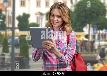 Giovane donna caucasica che usa un tablet in piedi all'aperto. Foto Stock