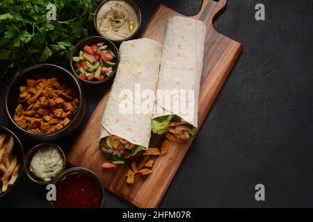 Sandwich arrotolato Shawarma con salsa e verdure, cibo tradizionale arabo. Shawarma Doner kebab wrap con pollo, patatine fritte e sottaceti. La Tradiitio israeliana Foto Stock