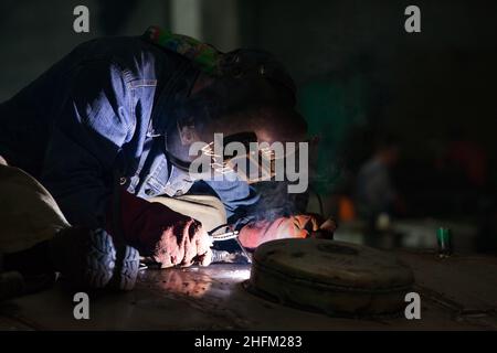 Saldatrice in lavoro. Sfondo scuro. Primo piano. Città di Uralsk, Kazakistan. Foto Stock