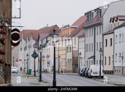 13 gennaio 2022, Brandeburgo, Baruth: Le auto sono parcheggiate di fronte agli edifici residenziali e commerciali sulla strada principale o sulla strada federale B 96. La piccola città nel distretto di Teltow-Fläming si trova vicino allo Spreewald ed è a poco meno di 50 chilometri dalla capitale. Baruth/Mark è stato menzionato per la prima volta in un documento nel 1234, poco dopo che un castello e un insediamento erano stati costruiti su una zona sabbiosa durante l'insediamento orientale tedesco. Foto: Soeren Stache/dpa-Zentralbild/ZB Foto Stock