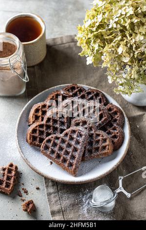 Cialde al cioccolato a forma di cuore in piastra di ceramica su sfondo testurizzato, vita ferma per San Valentino Foto Stock