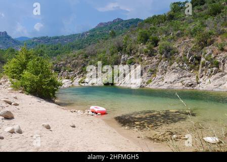 Anello di gomma rosa sul fiume Solenzara con acque turchesi e spiagge sabbiose ai piedi delle vette di Bavella nella Corsica del Sud, Francia. Phot di alta qualità Foto Stock