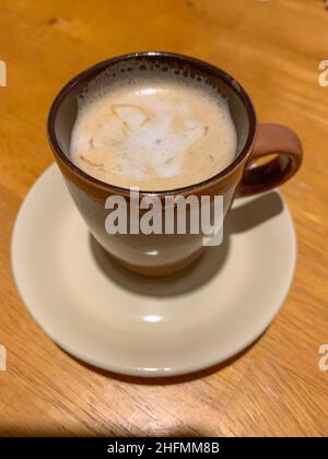 Piccola tazza marrone di caffè espresso caldo sul piatto. Foto di alta qualità Foto Stock