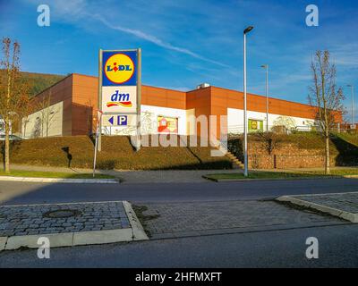 Neckargemuend, Germania - 02 gennaio 2022: Zona commerciale suburbana alla periferia di una piccola città tedesca con piloni di avviso per le catene di vendita al dettaglio Lidl (G Foto Stock