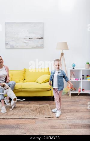 Sorridente ragazza che tiene slinky vicino a mamma e jack russell terrier a casa Foto Stock