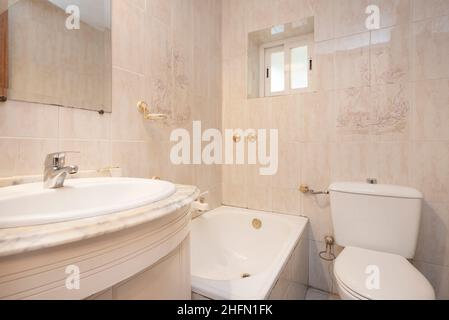 Bagno piastrellato con piastrelle color crema con piano in marmo bianco e vasca Foto Stock