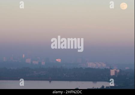 Frankley, Birmingham, Regno Unito. 17 gennaio 2022. La prima luna piena del 2022, chiamata Wolf Moon, sorge sopra Birmingham, circondata da una fitta foschia che blocca gran parte della sua vista dalle colline di Frankley, West Midlands. Il grande edificio bianco del Queen Elizabeth Hospital di Selly Oak è appena visibile sotto la luna. Fig. Per credito: Interrompi stampa Media/Alamy Live News Foto Stock