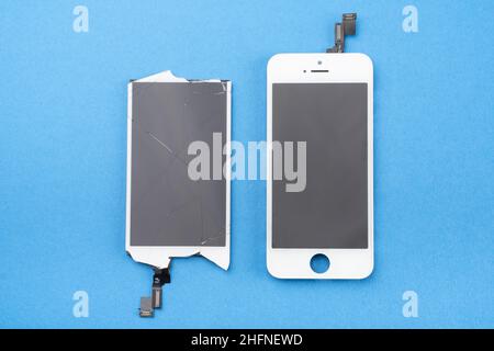 Praga, CZ - 16 gennaio 2022: Uno nuovo e uno usato schermo rotto su Blue bg. Il dispositivo è pronto per la riparazione. Editoriale Foto Stock