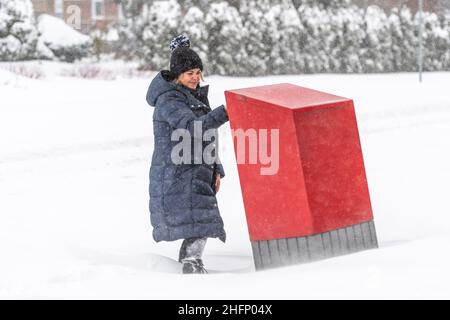 Una donna latino-americana invia una lettera in una casella di posta durante una tempesta invernale di neve a Toronto, Canada. Foto Stock