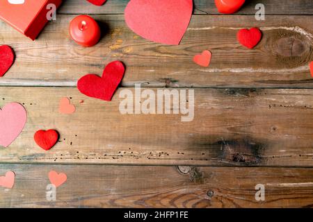 Vista dall'alto di candele rosse bruciate con decorazioni a forma di cuore da scatola regalo su tavola di legno Foto Stock