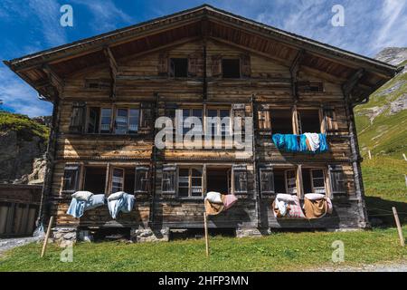 Un rifugio rustico e idilliaco con un cielo blu nella Valle di Lauterbrunnen. Le finestre sono aperte, la biancheria da letto è appesa all'aria. Foto Stock