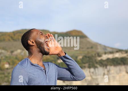 Ritratto laterale di un uomo con la pelle nera che urla in natura Foto Stock