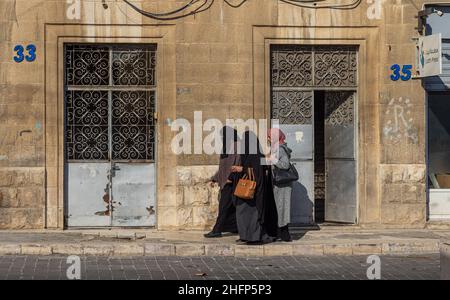 AMMA, GIORDANIA - 28 DICEMBRE 2021: Donne musulmane, vestite in un chador islamico, camminando per le strade il 28 dicembre 2021 ad Amman, Giordania Foto Stock