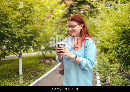 Ritratto di donna caucasica rilassante, mano che tiene tazzina di carta da asporto di caffè caldo con spazio copia. Foto Stock
