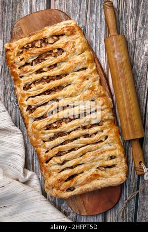 Una torta di strudel di mele in vimini con noci si trova su un tagliere Foto Stock