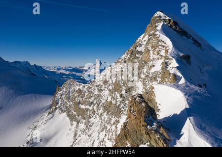 Spettacolare vista aerea della vetta dell'Allalin e del Cervino sullo sfondo delle alpi svizzere nel Cantone Vallese in Svizzera in una giornata invernale soleggiata Foto Stock