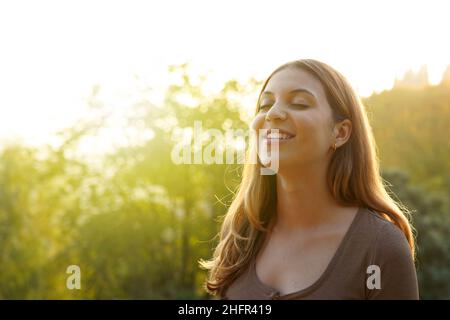 Bella donna respirando aria fresca su sfondo naturale. Spazio di copia. Foto Stock