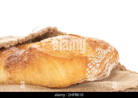 Una baguette francese appena sfornata su tessuto di iuta, primo piano, isolata su bianco. Foto Stock