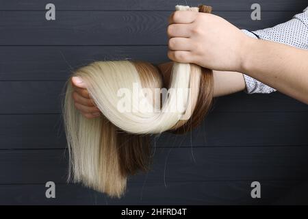 La mano maschio tiene le sezioni di capelli per l'estensione. Foto Stock