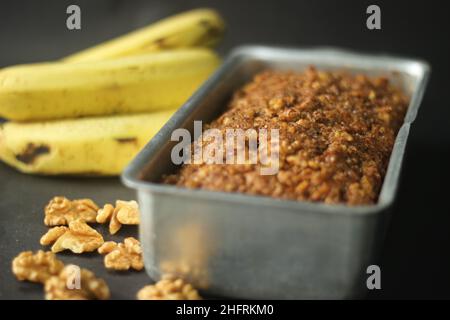 Pane alla banana fatto con farina integrale e olio di cocco. Cotto con cannella, zucchero e noce per un top croccante. Fresco da forno servito in un rectangu Foto Stock