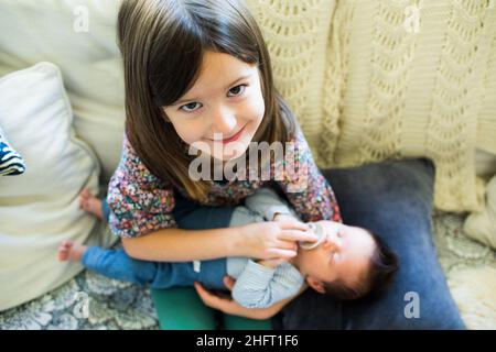 Alto angolo di sorella grande che tiene il suo fratello del bambino. Foto Stock
