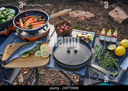 preparazione della cena al campo con trote e verdure farcite alle erbe. Foto Stock