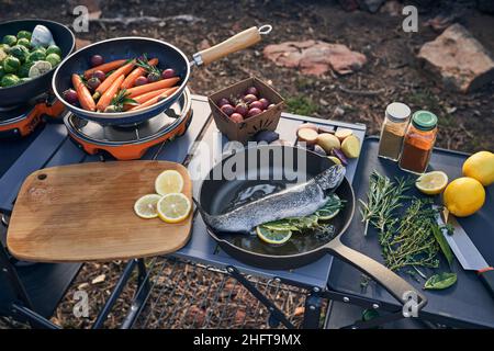 preparazione della cena al campo con trote e verdure farcite alle erbe. Foto Stock