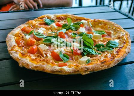 Pizza fresca con formaggio feta, basilico fresco e pomodori a tavola Foto Stock