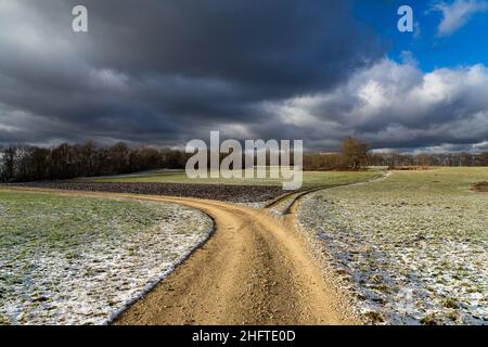 vista su un campo leggermente innevato in inverno con colori pastello Foto Stock